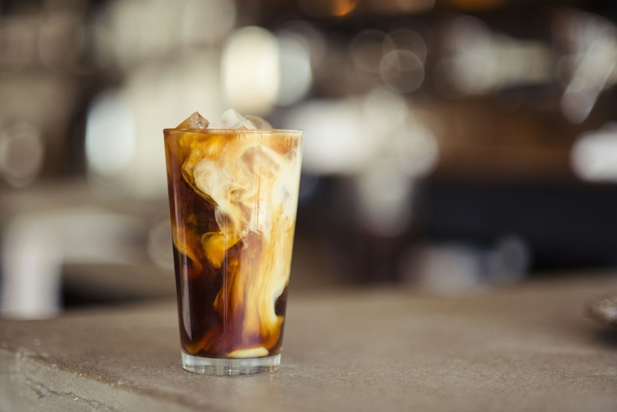 An iced latte in a glass on a wooden tabletop